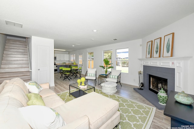 living room with a textured ceiling, light wood-type flooring, and a brick fireplace