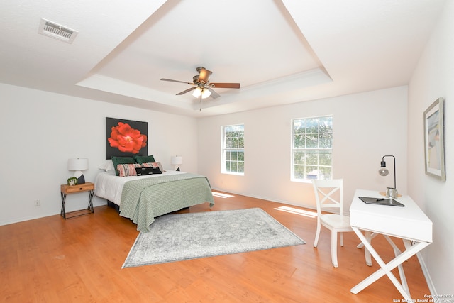 bedroom featuring a raised ceiling, ceiling fan, and wood-type flooring