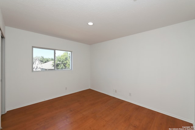 spare room featuring hardwood / wood-style flooring and a textured ceiling