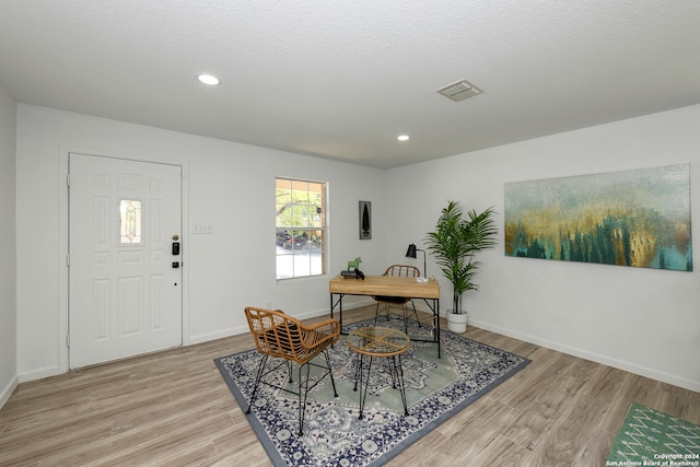 dining area featuring a textured ceiling and light hardwood / wood-style floors