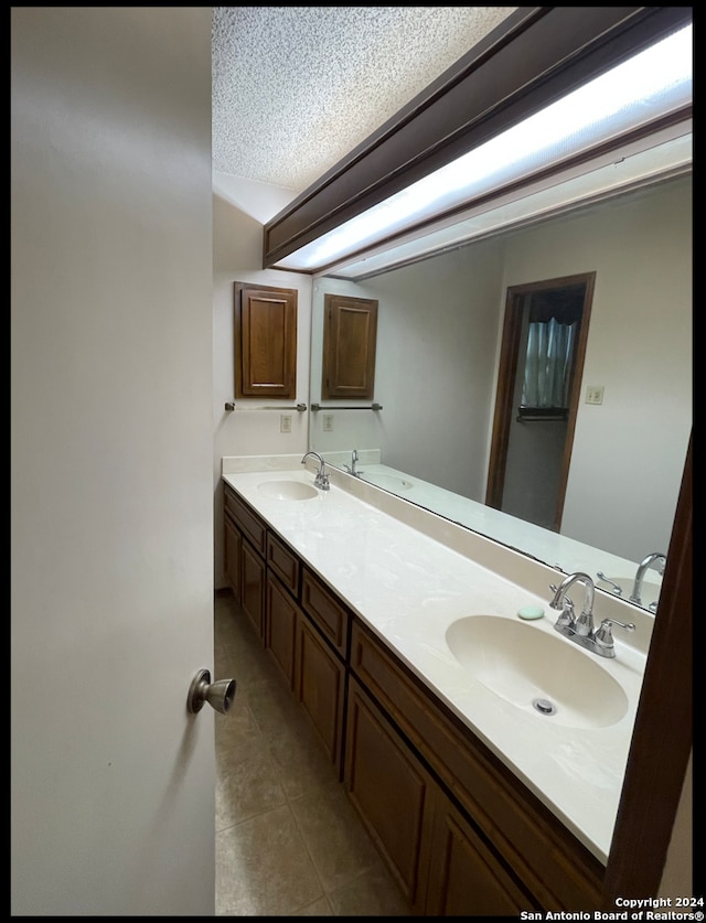 bathroom with tile patterned flooring, vanity, and a textured ceiling