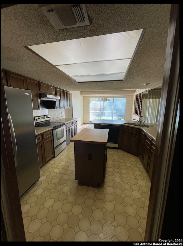 kitchen with a center island, sink, stainless steel appliances, a textured ceiling, and dark brown cabinets