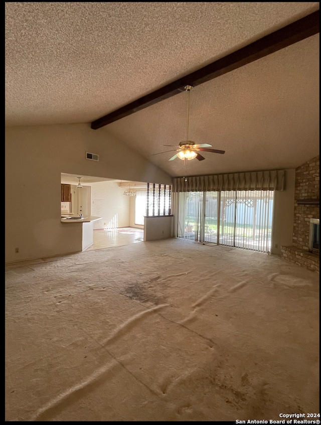 unfurnished living room with a fireplace, a textured ceiling, vaulted ceiling with beams, and ceiling fan