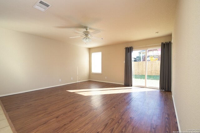 empty room featuring plenty of natural light, dark wood-type flooring, and ceiling fan