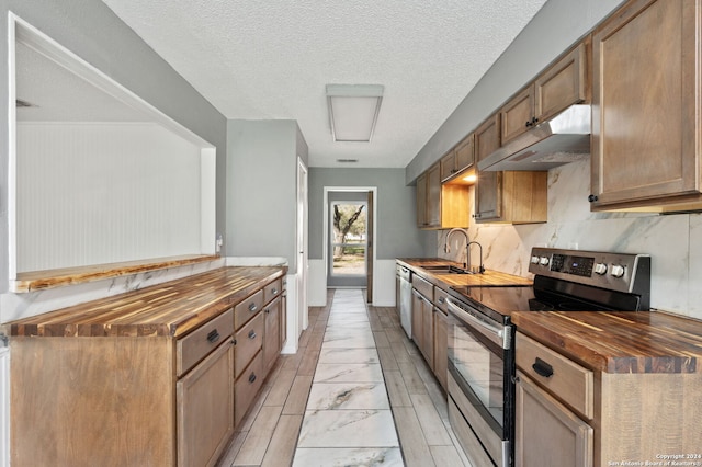 kitchen featuring butcher block counters, sink, stainless steel appliances, and a textured ceiling