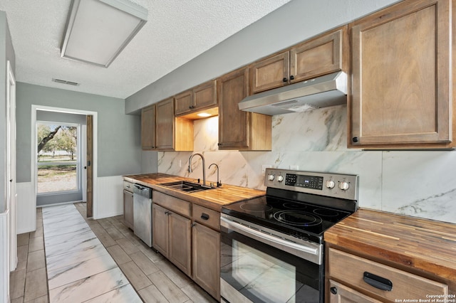 kitchen featuring butcher block countertops, sink, a textured ceiling, and appliances with stainless steel finishes