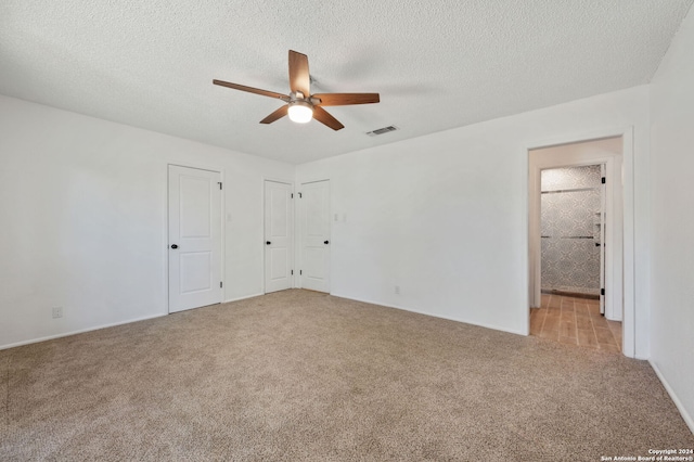 unfurnished bedroom featuring a textured ceiling, ceiling fan, light carpet, and connected bathroom