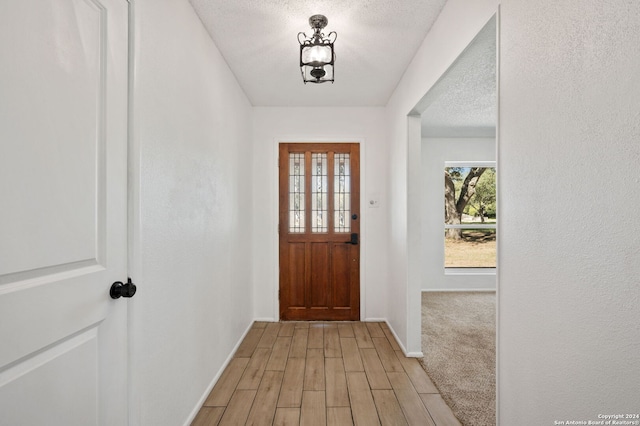 foyer entrance with a textured ceiling and light hardwood / wood-style floors