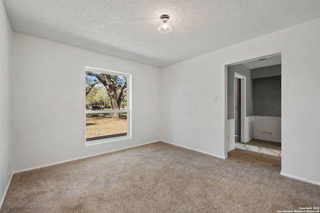 carpeted empty room with a textured ceiling