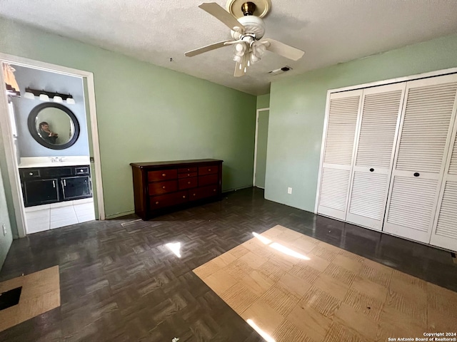 unfurnished bedroom featuring dark parquet flooring, sink, ceiling fan, a textured ceiling, and connected bathroom