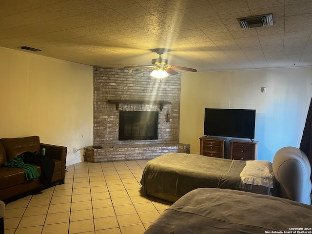 tiled bedroom featuring ceiling fan and a brick fireplace