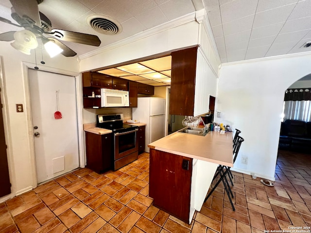 kitchen with kitchen peninsula, white appliances, a breakfast bar area, and ornamental molding