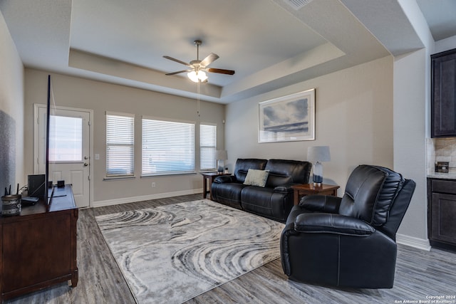 living room with hardwood / wood-style floors, ceiling fan, and a tray ceiling