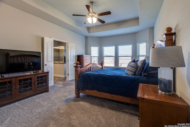 bedroom featuring carpet, connected bathroom, a raised ceiling, and ceiling fan