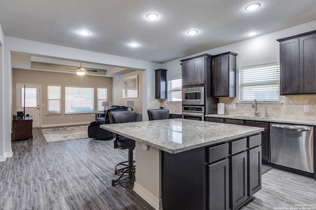 kitchen with a textured ceiling, stainless steel appliances, a kitchen island, and sink