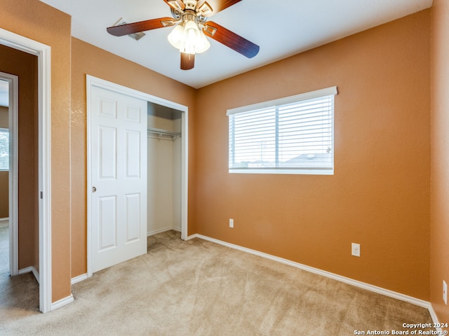 unfurnished bedroom featuring ceiling fan, light colored carpet, and a closet