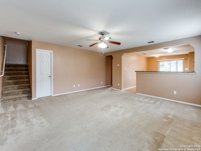 unfurnished living room featuring ceiling fan and light colored carpet