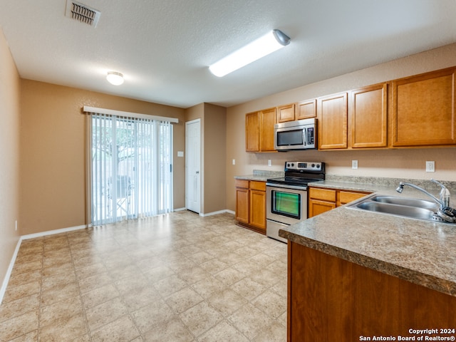 kitchen featuring a textured ceiling, sink, and appliances with stainless steel finishes