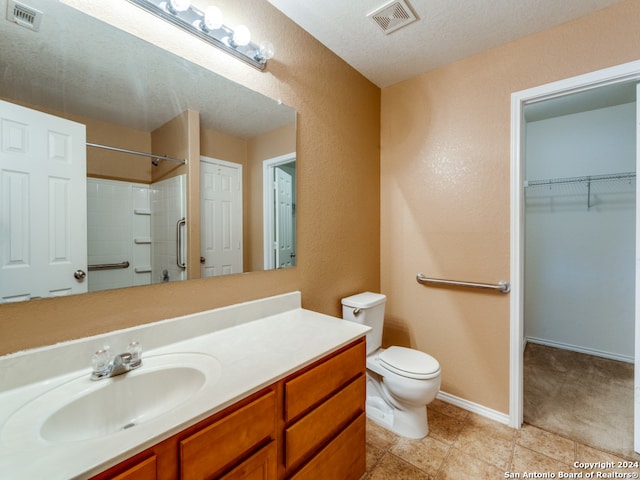 bathroom featuring a textured ceiling, vanity, a shower, tile patterned flooring, and toilet