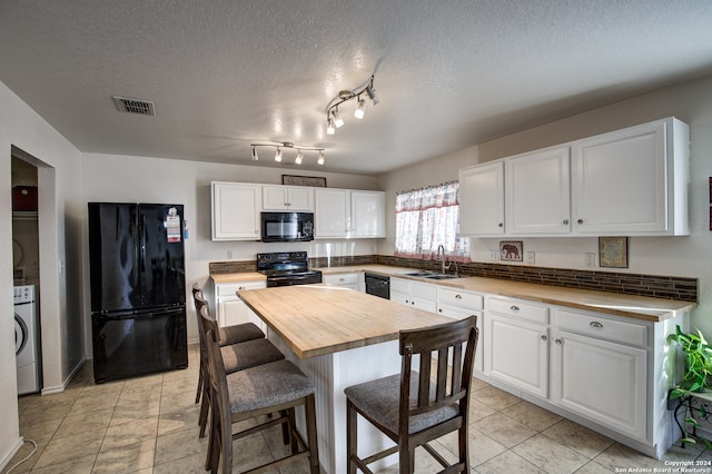 kitchen featuring a textured ceiling, black appliances, washer / clothes dryer, white cabinetry, and butcher block counters