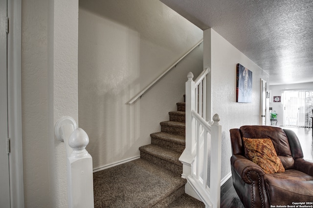 stairway featuring carpet flooring and a textured ceiling