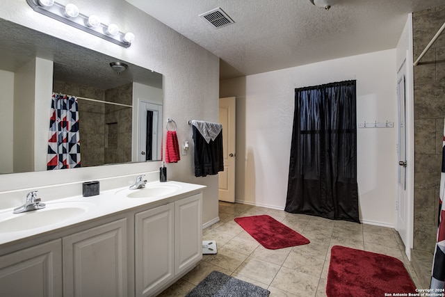 bathroom featuring tile patterned flooring, vanity, a textured ceiling, and walk in shower