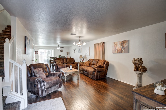 living room featuring ceiling fan with notable chandelier, a textured ceiling, and hardwood / wood-style flooring