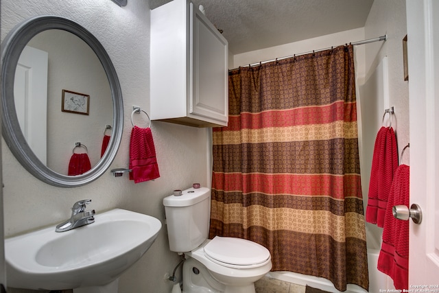 full bathroom with shower / bath combo, a textured ceiling, toilet, and sink