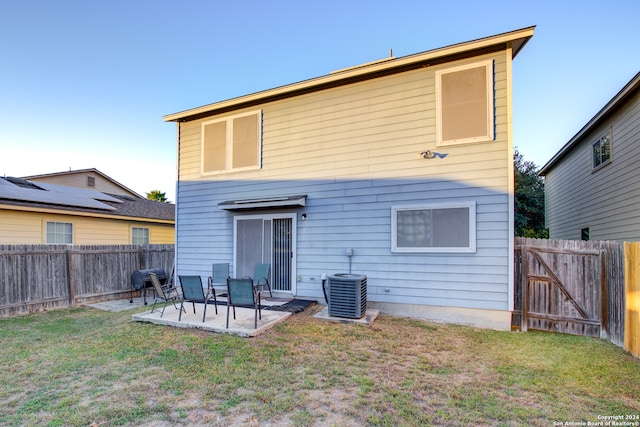 rear view of property with a patio, central AC, and a lawn