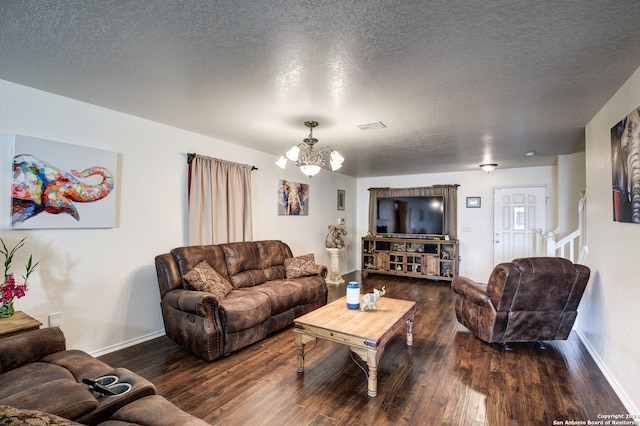 living room with dark wood-type flooring, a textured ceiling, and an inviting chandelier