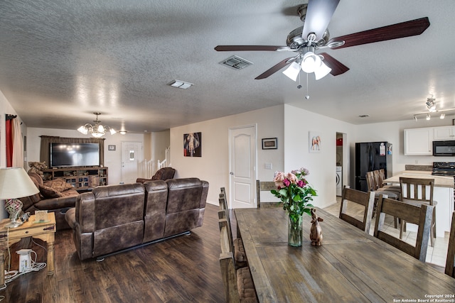 dining area featuring ceiling fan with notable chandelier, dark wood-type flooring, a textured ceiling, and washer / dryer