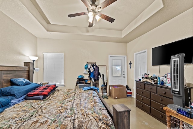 bedroom featuring ceiling fan, a raised ceiling, and a textured ceiling