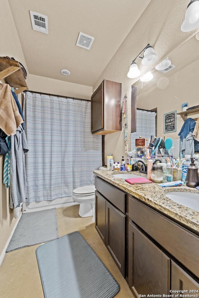 full bathroom with shower / bathtub combination with curtain, vanity, a textured ceiling, and toilet