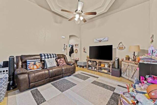 living room with a tray ceiling and ceiling fan