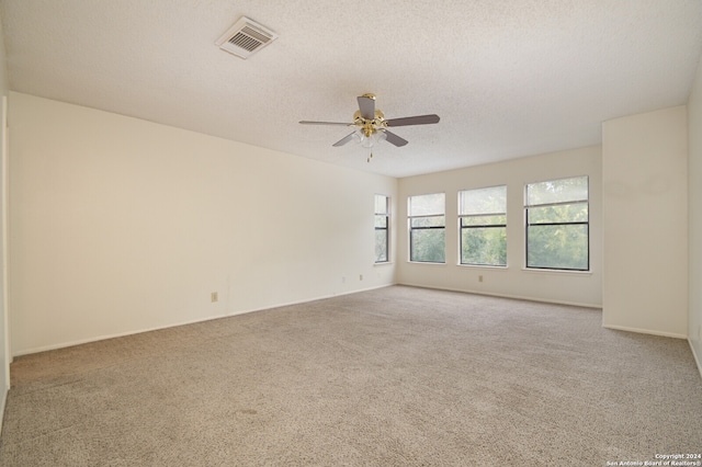 carpeted spare room with a textured ceiling and ceiling fan