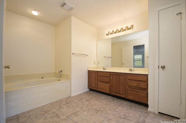 bathroom featuring a bathing tub, vanity, and a textured ceiling