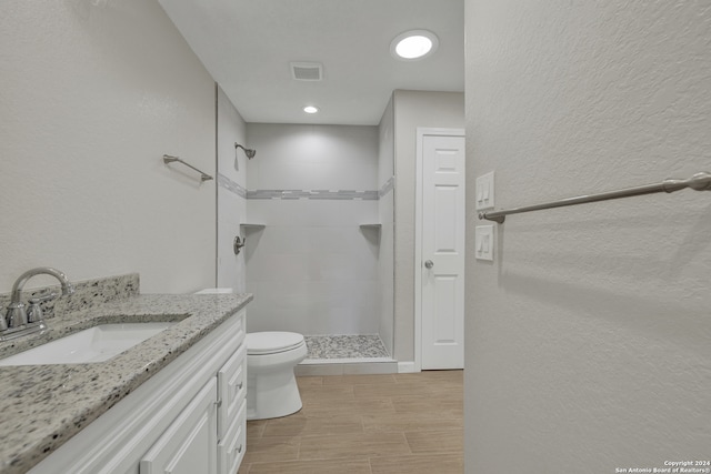 bathroom with toilet, vanity, and tiled shower