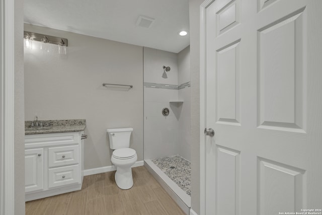 bathroom with vanity, toilet, and a tile shower