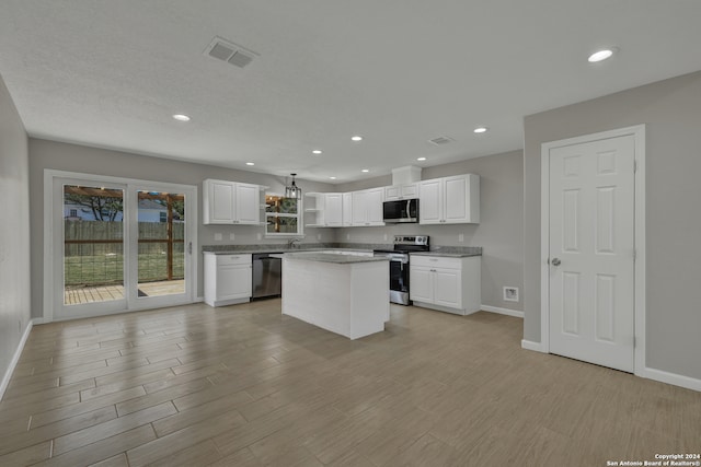 kitchen with white cabinets, appliances with stainless steel finishes, a center island, and light hardwood / wood-style flooring