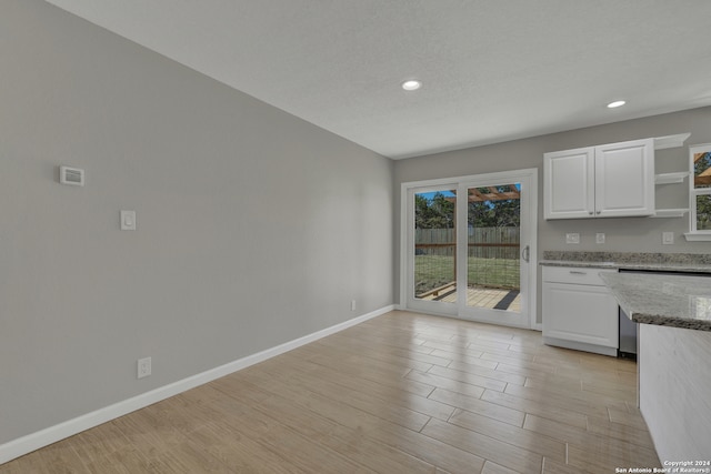 kitchen with light wood-type flooring, stone countertops, and white cabinetry