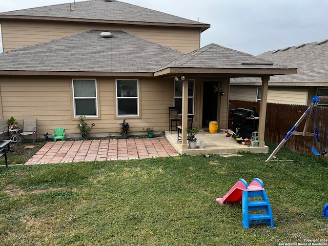 rear view of property with a playground, a patio area, and a yard