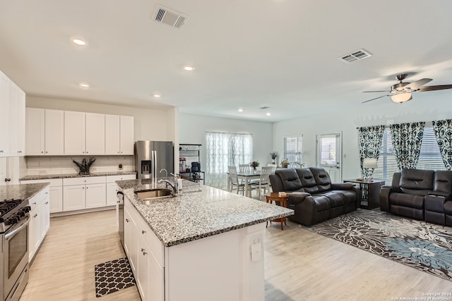 kitchen featuring a kitchen island with sink, white cabinets, sink, tasteful backsplash, and stainless steel appliances