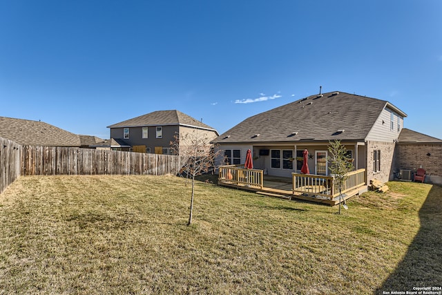 rear view of property with a yard, cooling unit, and a deck