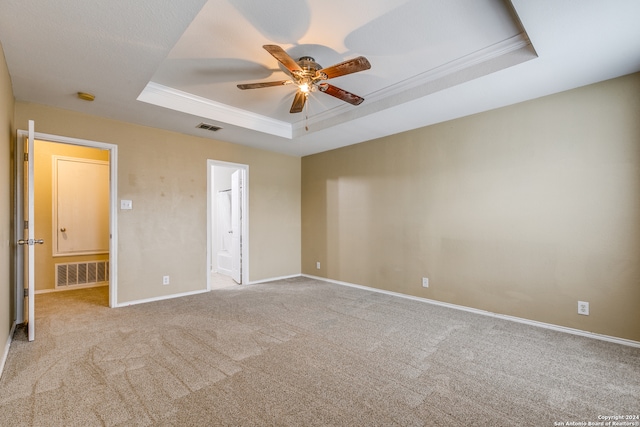 carpeted spare room with a tray ceiling, ceiling fan, and ornamental molding