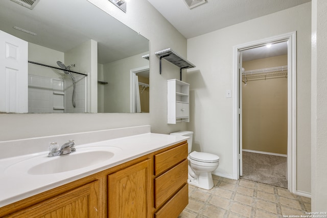 bathroom with toilet, vanity, a textured ceiling, and walk in shower