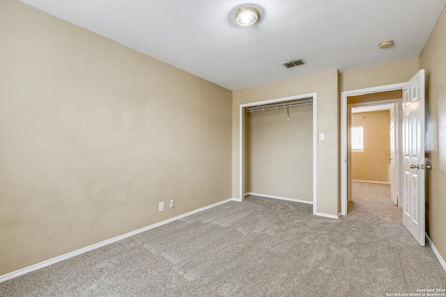 unfurnished bedroom featuring light carpet and a closet