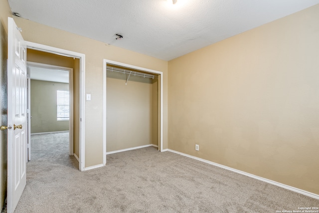 unfurnished bedroom featuring light carpet, a textured ceiling, and a closet