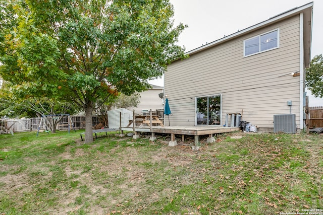 back of house with a lawn, cooling unit, a storage shed, and a deck