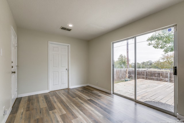 spare room with hardwood / wood-style floors, a healthy amount of sunlight, and a textured ceiling