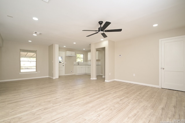 unfurnished living room with a wall mounted AC, light hardwood / wood-style floors, and ceiling fan